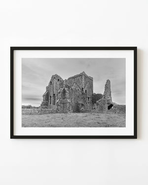 Hore Abbey’s stone ruins stand in an Irish field beneath a cloudy sky, photographed in black and white.
