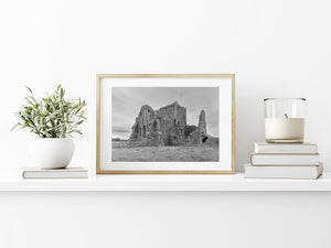 Ireland’s Hore Abbey ruins rise above grass and low stone walls under an overcast sky.