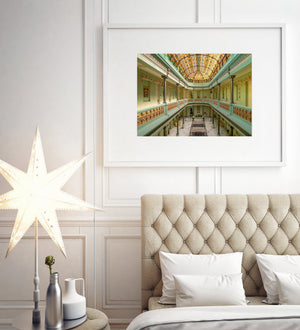 Colour photograph of Hotel Raquel’s elegant green atrium beneath orange and green stained glass.