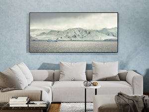 Antarctic coastal landscape with snow-covered peaks and dark exposed rock above the sea.