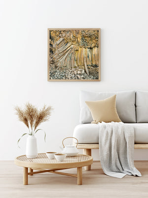 Close view of fractured volcanic columns in earthy gold, grey and muted green tones.