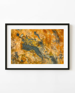 Aerial view of a grey geothermal mud basin amid orange and yellow mineral-stained ground in Iceland.