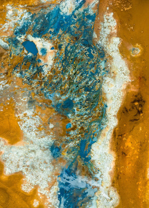 An overhead view of Iceland’s mineral basin, with vivid blue water amid ochre and pale deposits.