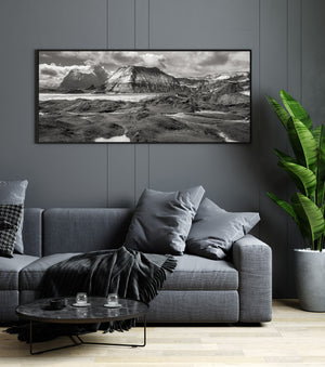 Reflective pools break up dark volcanic ground beneath towering Icelandic mountain ridges.