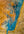 A blue-green channel curves across ochre geothermal terrain in an abstract Icelandic aerial view.