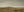 A herd of Icelandic horses stands on a low ridge in an earth-toned rural landscape.