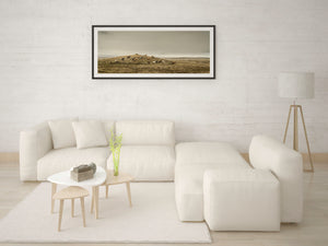 Horses dot a grassy ridge in a wide Icelandic landscape with soft, hazy light.