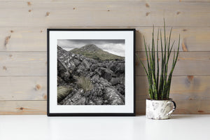 Muted colour landscape of layered rocks and windswept grass along Ireland’s Inch Beach coast.