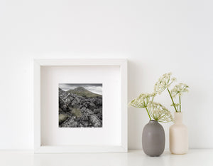 Dark textured rocks and pale green grass in a quiet Irish coastal landscape.