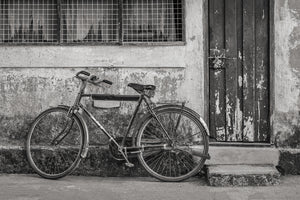 old bicycle beside peeling paint door monochrome street scene