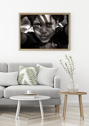 Warm monochrome portrait of an Indian girl with patterned clothing and sunlit eyes.