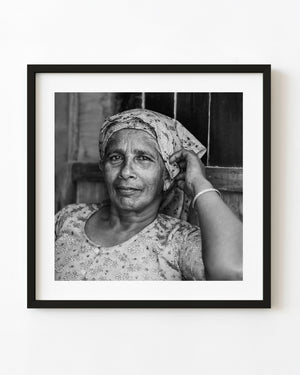 Black and white portrait of an elderly woman seated inside a shop in India