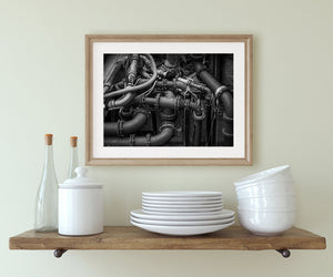 Black and white mechanical photograph with intersecting pipes, valve fittings and textured iron surfaces.