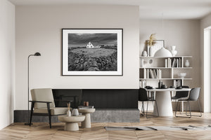 An Irish countryside cottage with a pitched roof beside a quiet road and enclosed meadow.