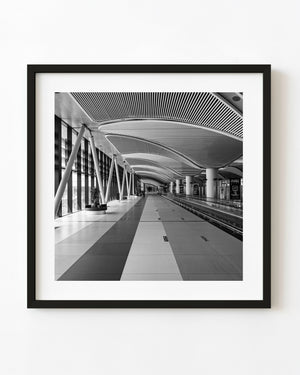 Black and white Istanbul airport corridor with repeating curved ceiling panels and a long central walkway.