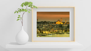 Istanbul cityscape at dusk with mosque minarets rising above rooftops and waterfront boats.