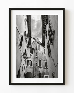 Black and white view looking up an Italian alley with shuttered windows, lanterns and weathered walls.