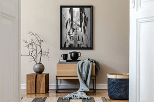 Decorative wall lanterns and dark window shutters along a narrow Italian passage.