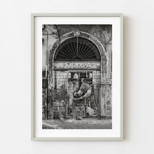 Black and white mural of woman working on metal shop shutter in Tivoli