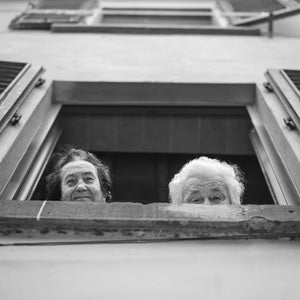 Black and white street portrait of senior women at a window in Tuscany  