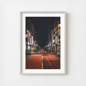 Tokyo street at night with red roadway and illuminated shops