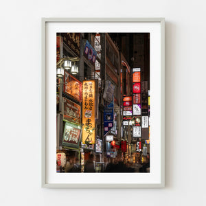 Neon restaurant and bar signs stacked along a Shinjuku Tokyo street at night