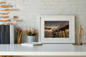 Colour photograph of a Florida pier beneath an orange morning sky