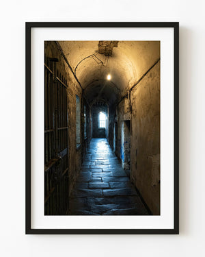 Arched corridor at Kilmainham Gaol with warm light and a distant window