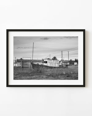 Abandoned Lake Nipigon charter boat standing in tall grass in black and white.