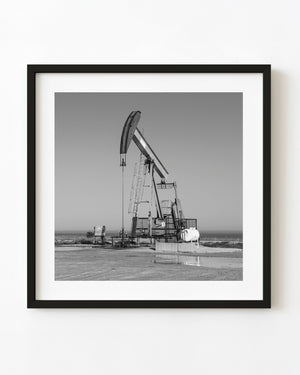 Oil pumpjack on the shores of Lake Ontario in black and white.