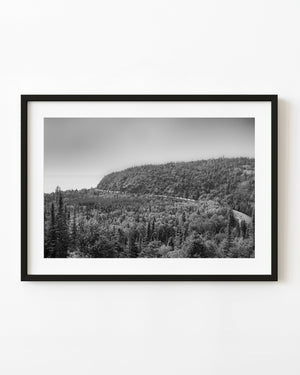 Railway curves through forest beside Lake Superior in black and white.