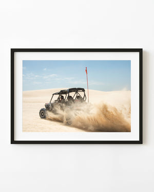 Dune buggy throws sand while racing across Lancelin dunes beneath a blue sky.
