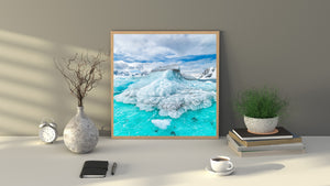Floating ice fragments surround a textured iceberg near snow-covered Antarctic peaks.