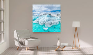 Blue-white Antarctic ice contrasts with turquoise water and distant mountain slopes.