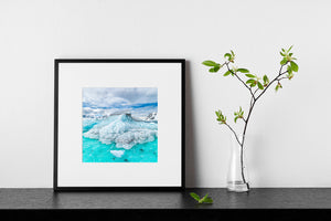 Layered iceberg and small floating ice pieces beneath a pale Antarctic sky.