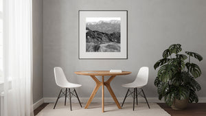 Rugged dark hills rise behind smooth pale ridges in a layered mountain landscape.