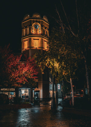 Warm lights outline LeTAO’s brick tower above a wet Otaru street.