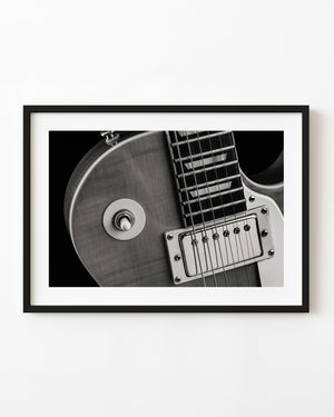 Black and white close-up of a Les Paul guitar’s toggle switch, strings and pickup