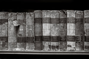 Row of old books with visible wear on a shelf against a black background