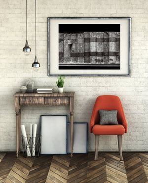 Modern interior with a wooden console table, red chair, and framed artwork on a white brick wall.
