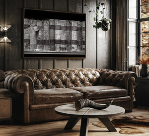 Brown leather sofa in a room with wooden walls and a decorative table.