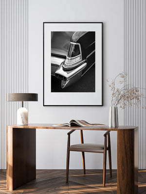 Gerahmtes Schwarz-Weiß-Foto eines Autos an einer Wand über einem Holzschreibtisch mit Stuhl.