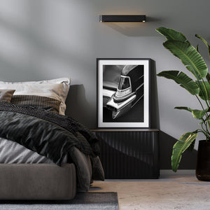 Modern bedroom with a bed, framed black and white photo, and plant.