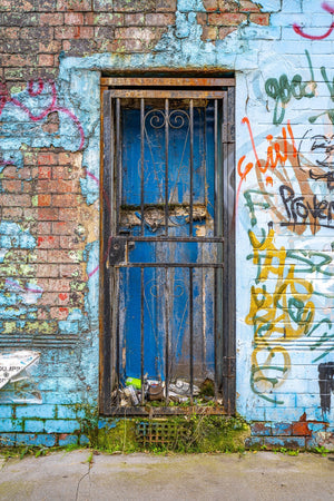 Blue wooden doorway in a peeling painted brick wall with colourful London graffiti