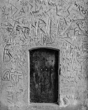 Recessed timber door with scratched graffiti in historic London building