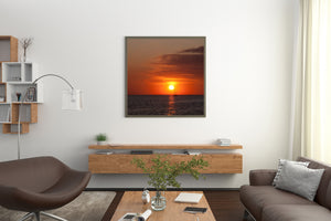 Silhouetted sailboat beside a golden sun beneath layered sunset clouds