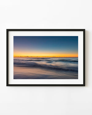 Blue ocean waves beneath a golden dawn horizon at Long Reef Beach