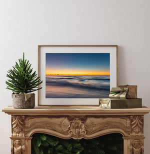 Golden light on the horizon above smooth blue ocean waves at dawn