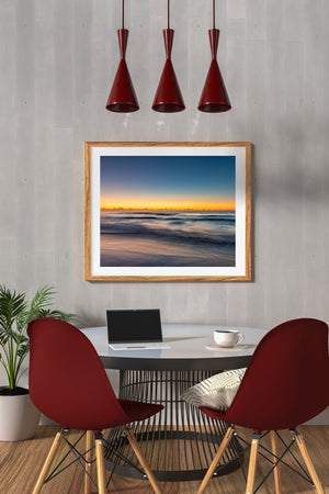 Quiet Long Reef Beach seascape with rolling surf beneath a glowing golden sky