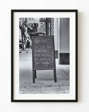 Love your enemies chalkboard sign on a New York sidewalk in black and white